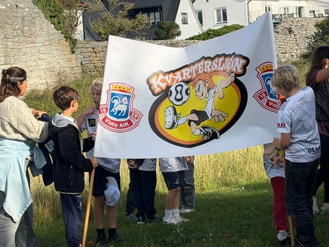 Group of children and adults holding a large Brewskis logo banner outdoors on grass