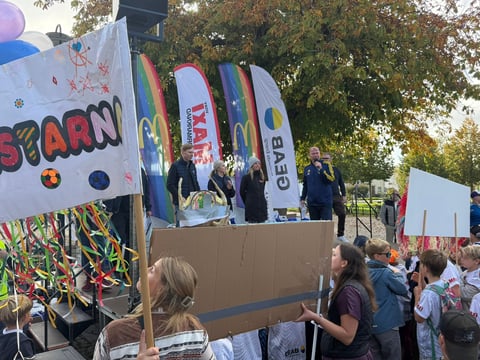 Colorful carnival or fair parade float with YARN text and spinning elements, surrounded by spectators in an outdoor park setting